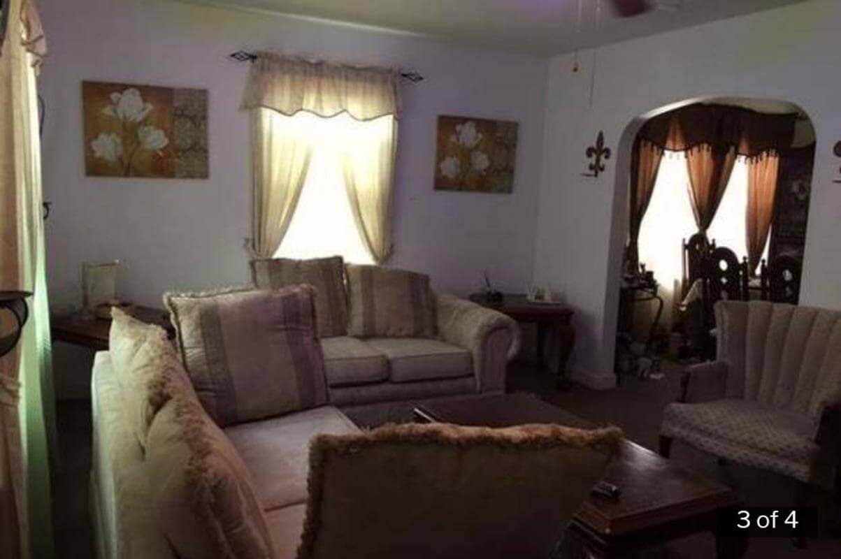 The living room with outdated furniture, carpet, and low light