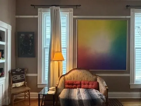 Living room with a large gradient abstract painting, an upholstered antique sofa, a floor lamp, and layered rugs.