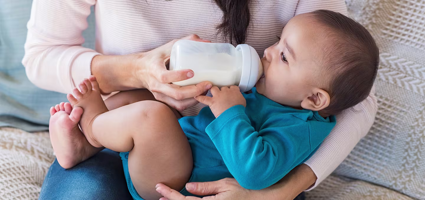 Image of a caregiver bottle-feeding an infant