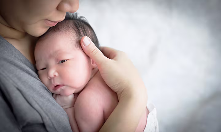 Mutter hält neugeborenes Baby sicher auf dem Arm