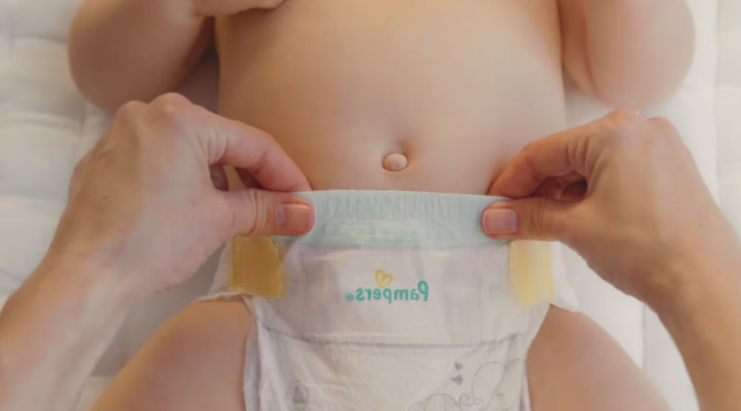 En närbild visar två händer som håller en Pampers blöja, vilket avslöjar Flex & Protect-linning