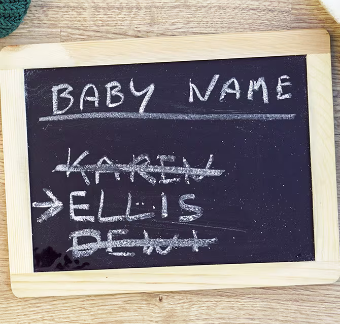 Kreidetafel mit der Überschrift Baby Name und durchgestrichenen Namensvorschlägen – Symbolbild für die Suche nach dem perfekten Babynamen
