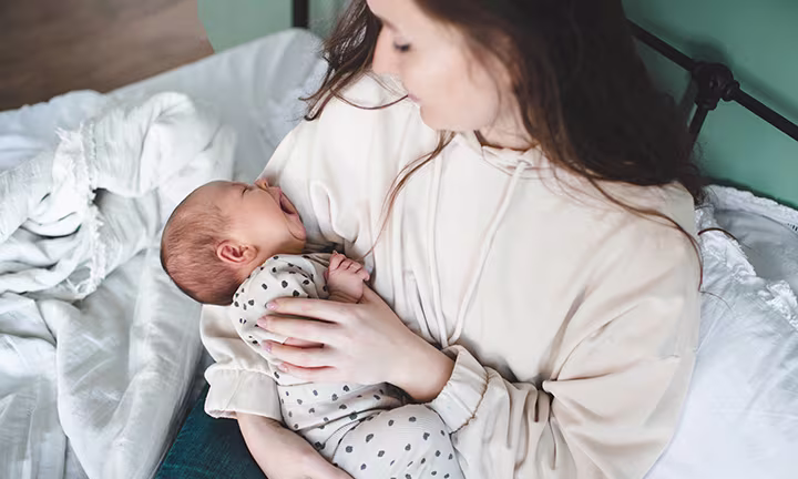 Baby lying on its mother's arm