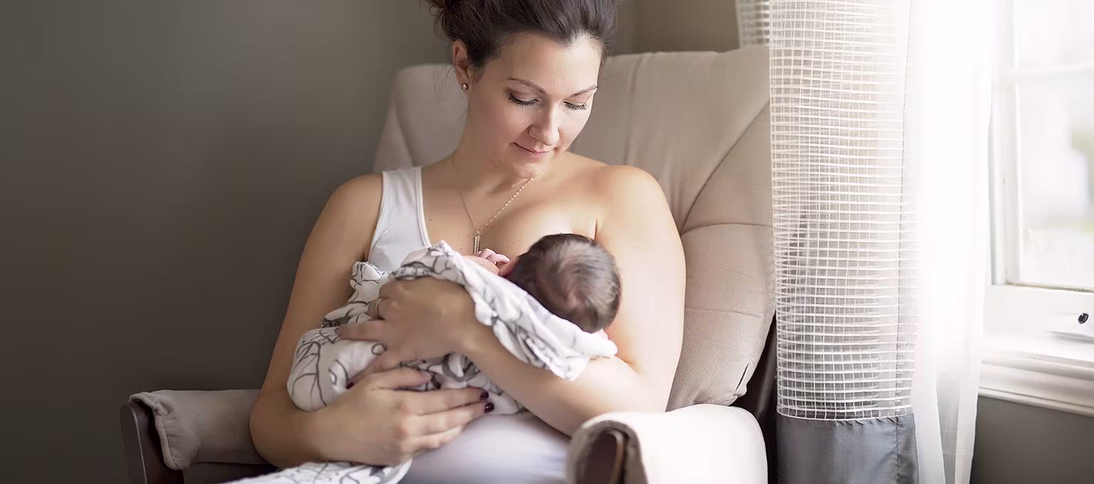 Mère allaitant son bébé dans un fauteuil.