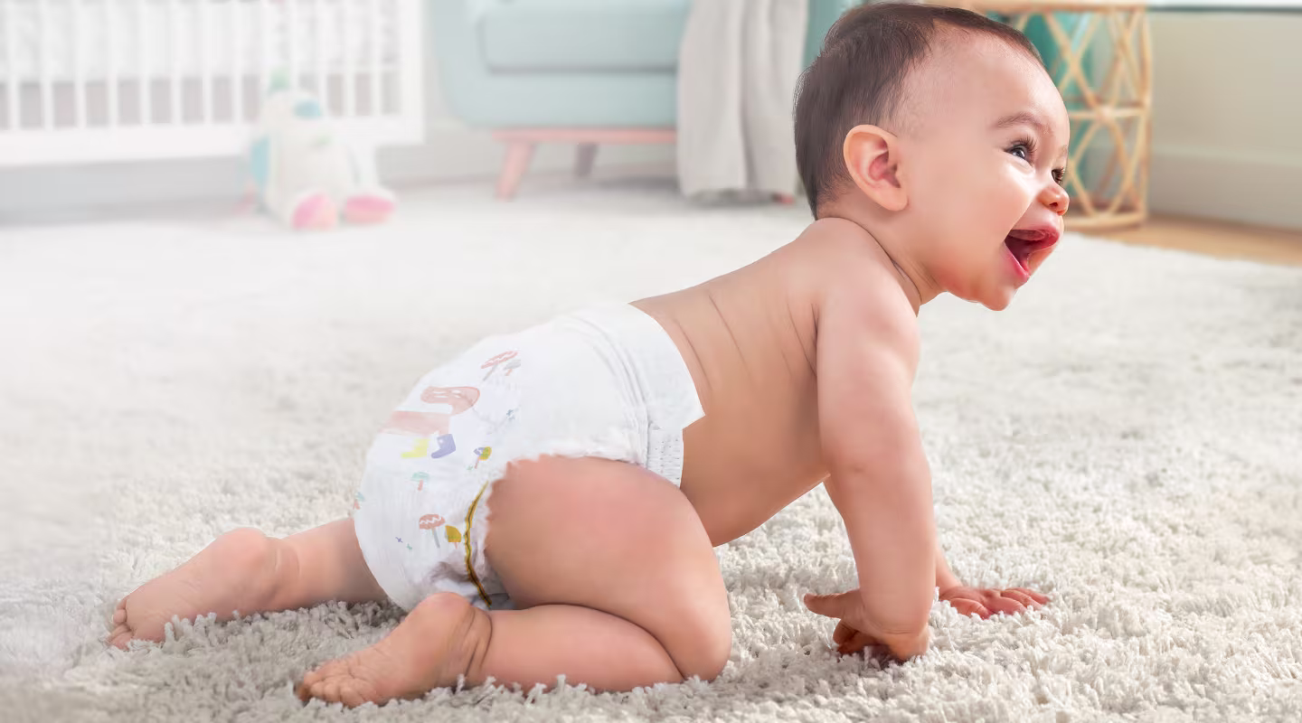 A crawling laughing baby wearing a Pampers nappy
