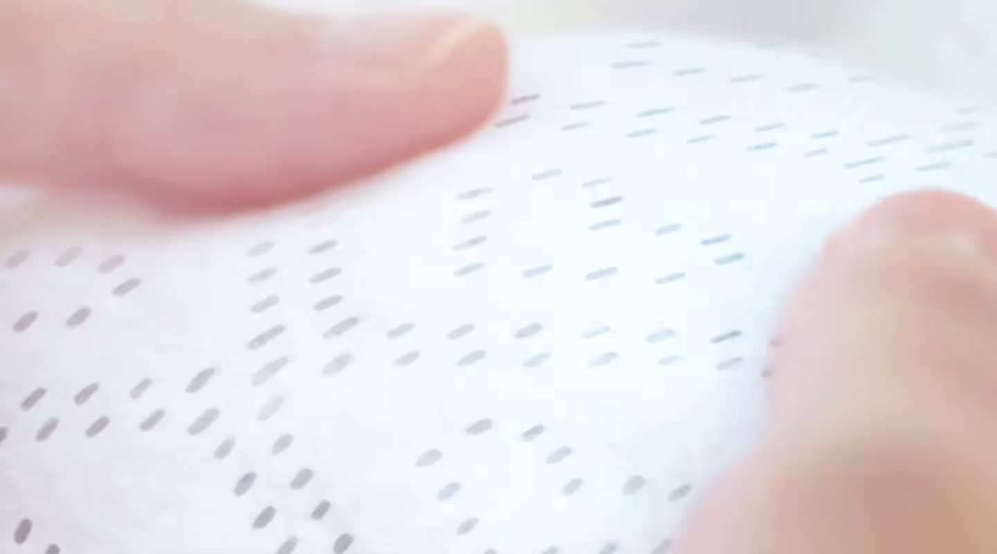 Um close-up mostra duas mãos segurando delicadamente uma fralda Dodot de textura suave, destacando o seu padrão de pontos e a sua sensação fofa.