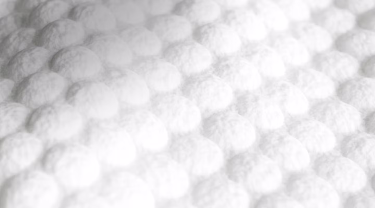 An extreme close-up of a wipe with soft, white absorbent material, showing a quilted, dimpled texture.