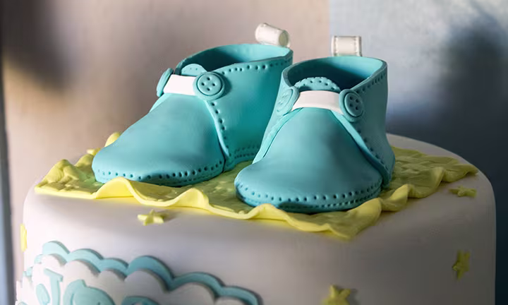 Le gâteau avec des chaussures de bébé Gâteau de naissance avec chaussons bleus en pâte à sucre, nuages et étoiles jaunes