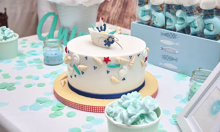 Table de baptême thème marin avec gâteau, confettis, bonbons et décoration bord de mer