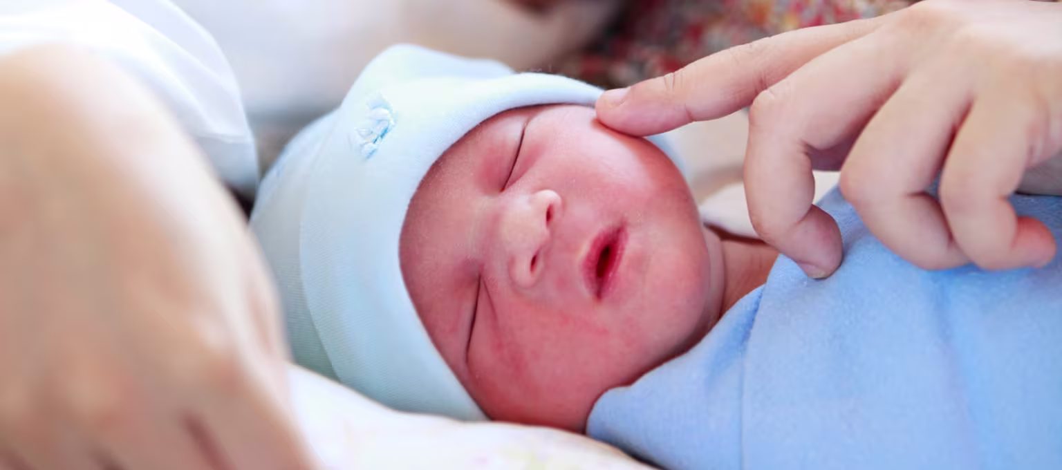 Maman caressant son bébé prématuré