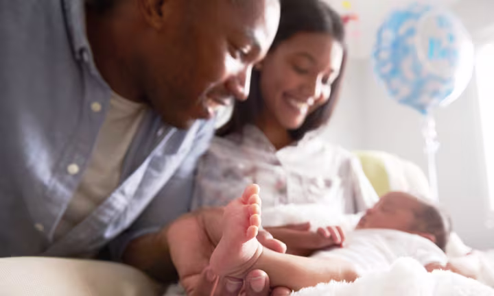 Mutter und Vater schauen ihrem Baby beim Schlafen zu
