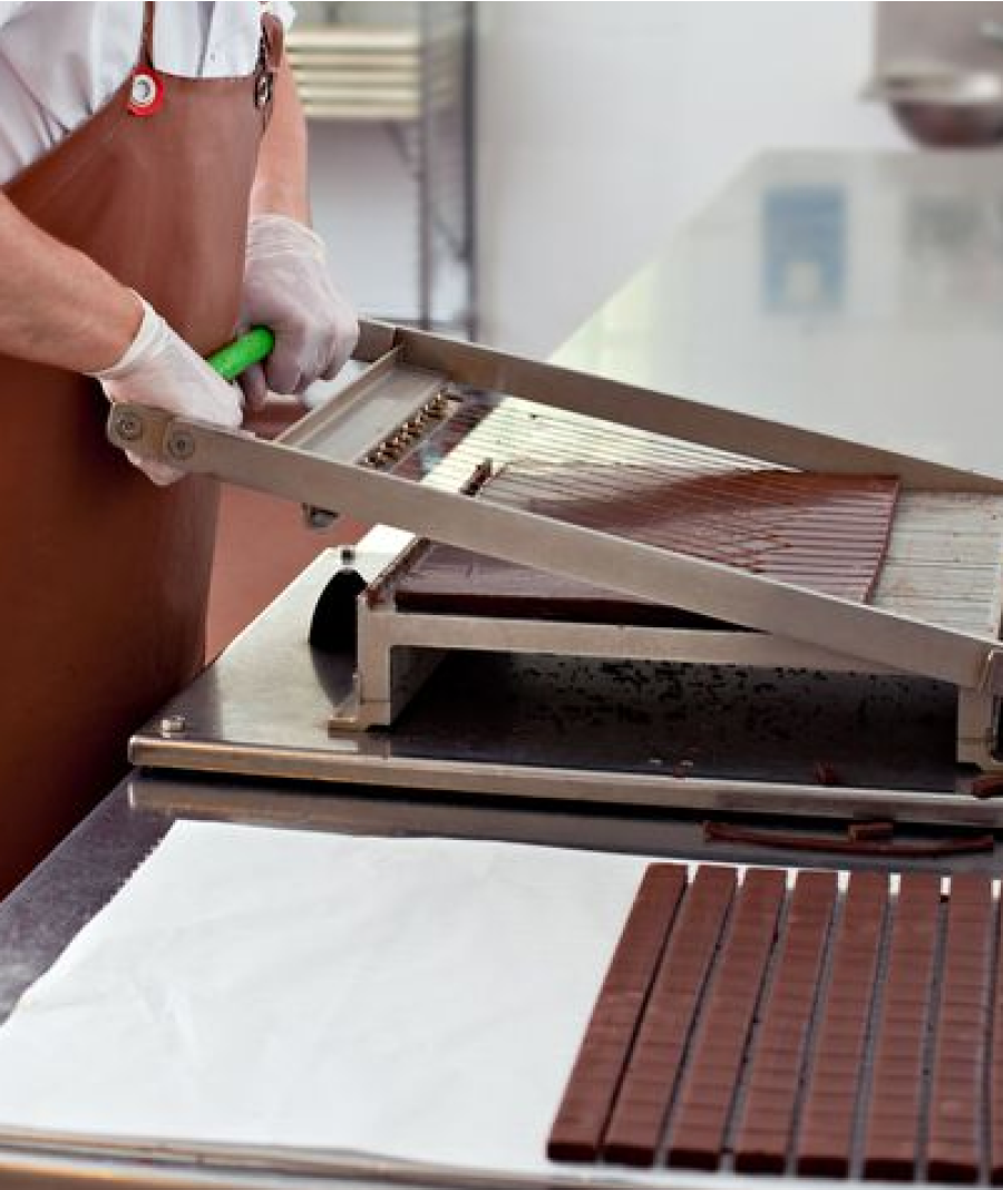 Man Using Chopper To Cut Chocolate Into Strips