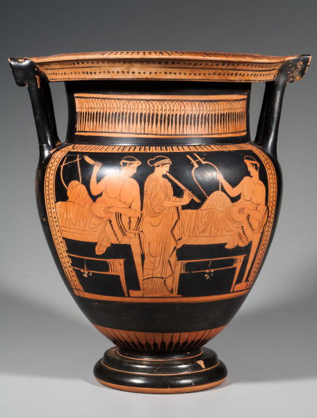 A vessel with two column-like handles has ornamental patterns around the neck and on the wide, flattened rim. The scene on the visible side of the bowl's body depicts three youths standing together in conversation.