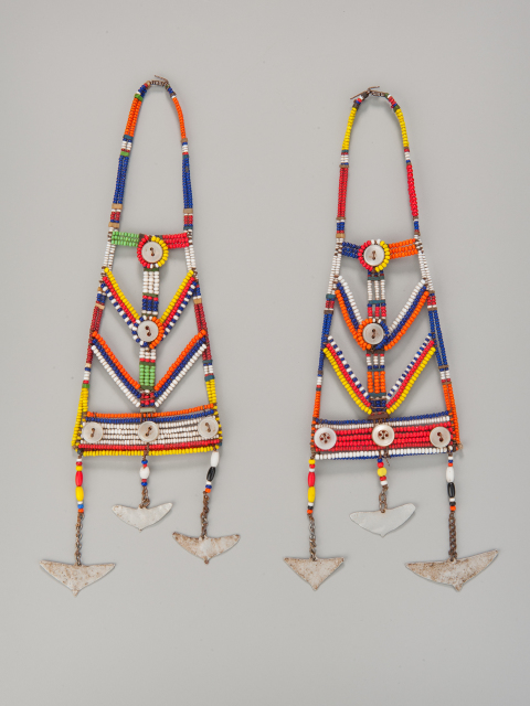 Multicolored bead earrings with narrow loops at the top and dangling triangular metal shapes at the bottom. The earrings include geometric patterns composed of multicolored beads and buttons, each ending in a rectangular bar also made of beads and buttons.
