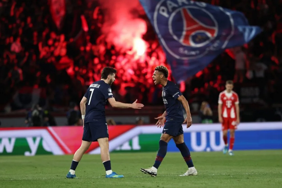 Paris Saint-Germain's Georgian forward #07 Khvicha Kvaratskhelia (L) celebrates with Paris Saint-Germain's French midfielder #14 Desire Doue after scoring his team first goal during the UEFA Champions League semi-final first leg football match between Paris Saint-Germain (PSG) and Bayern Munich at the Parc des Princes in Paris on April 28, 2026.  Anne-Christine POUJOULAT / AFP