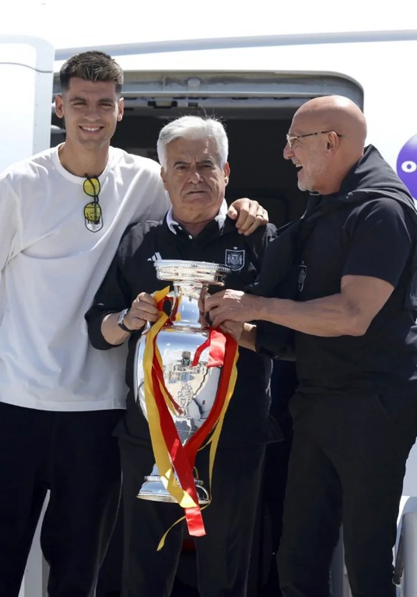 Spain's forward #07 Alvaro Morata (L), Spanish football federation president Pedro Rocha (C) and Spain's head coach Luis de la Fuente (R) pose with the UEFA Euro 2024 trophy while arriving at Adolfo Suárez Madrid-Barajas Airport in Madrid on July 15, 2024, the day after winning the final against England.  OSCAR DEL POZO / AFP