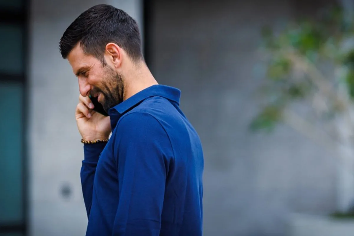 Serbia's Novak Djokovic talks on his phone during a press conference ahead of the Brisbane International tennis tournament at the Patrick Rafter Tennis Centre in Brisbane on December 29, 2024.   Patrick HAMILTON / AFP