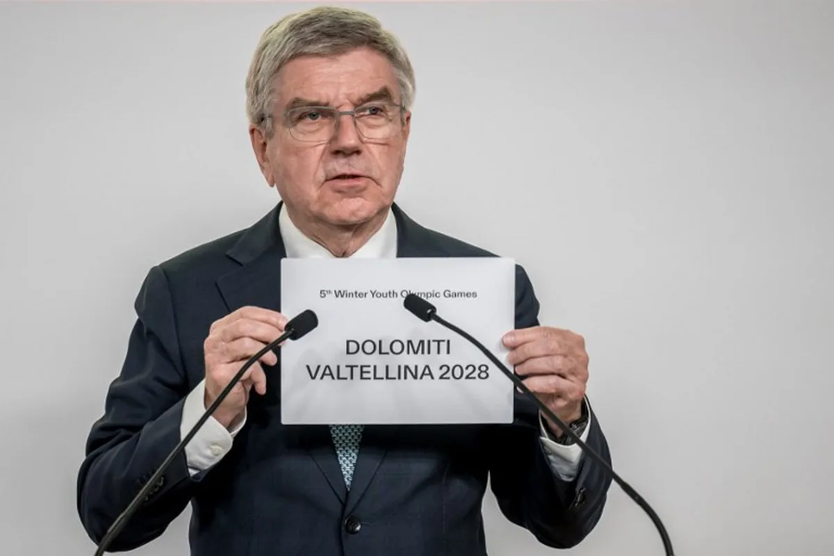 International Olympic Committee (IOC) President Thomas Bach holds a sheet of paper that reads 'Dolomiti Valtellina 2028' after Italy's Dolomiti Valtellina was confirmed as host of the 2028 Winter Youth Olympic Games (YOG), in a vote by the 143rd IOC Session, in Lausanne on January 30, 2025.  FABRICE COFFRINI / POOL / AFP