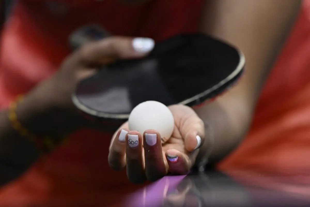 A detailed view of India's Manika Batra's nails painted with the Indian flag and Olympic Rings as she prepares to serve the ball during her women's table tennis singles match in the team quarter-finals between India and Germany at the Paris 2024 Olympic Games at the South Paris Arena in Paris on August 7, 2024.  WANG Zhao / AFP