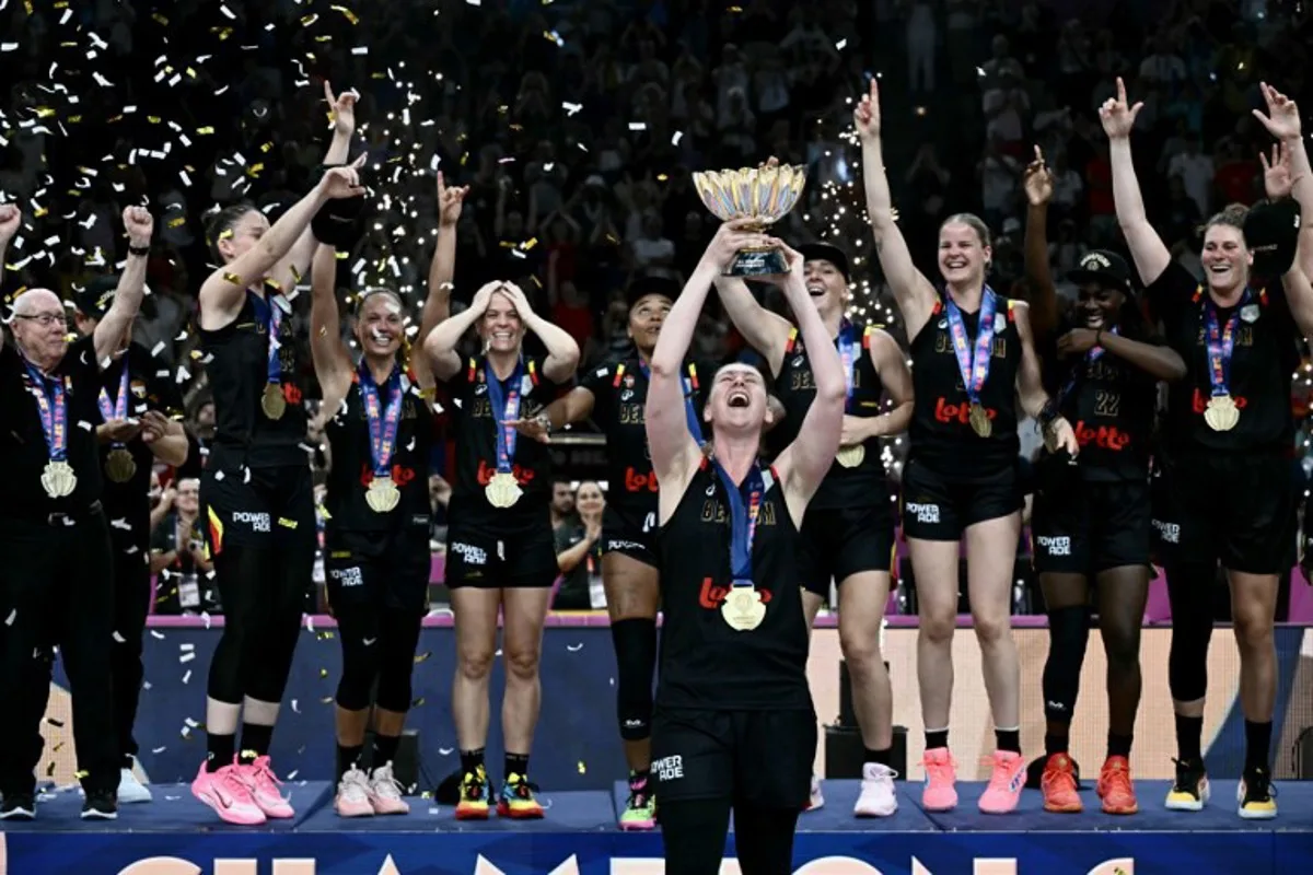 Belgium's power forward Emma Meesseman (C) holds the trophy and celebrates with teammates winning the 2025 FIBA Women's EuroBasket after their final match against Spain at the Peace and Friendship Stadium in Athens on June 29, 2025. Aris MESSINIS / AFP