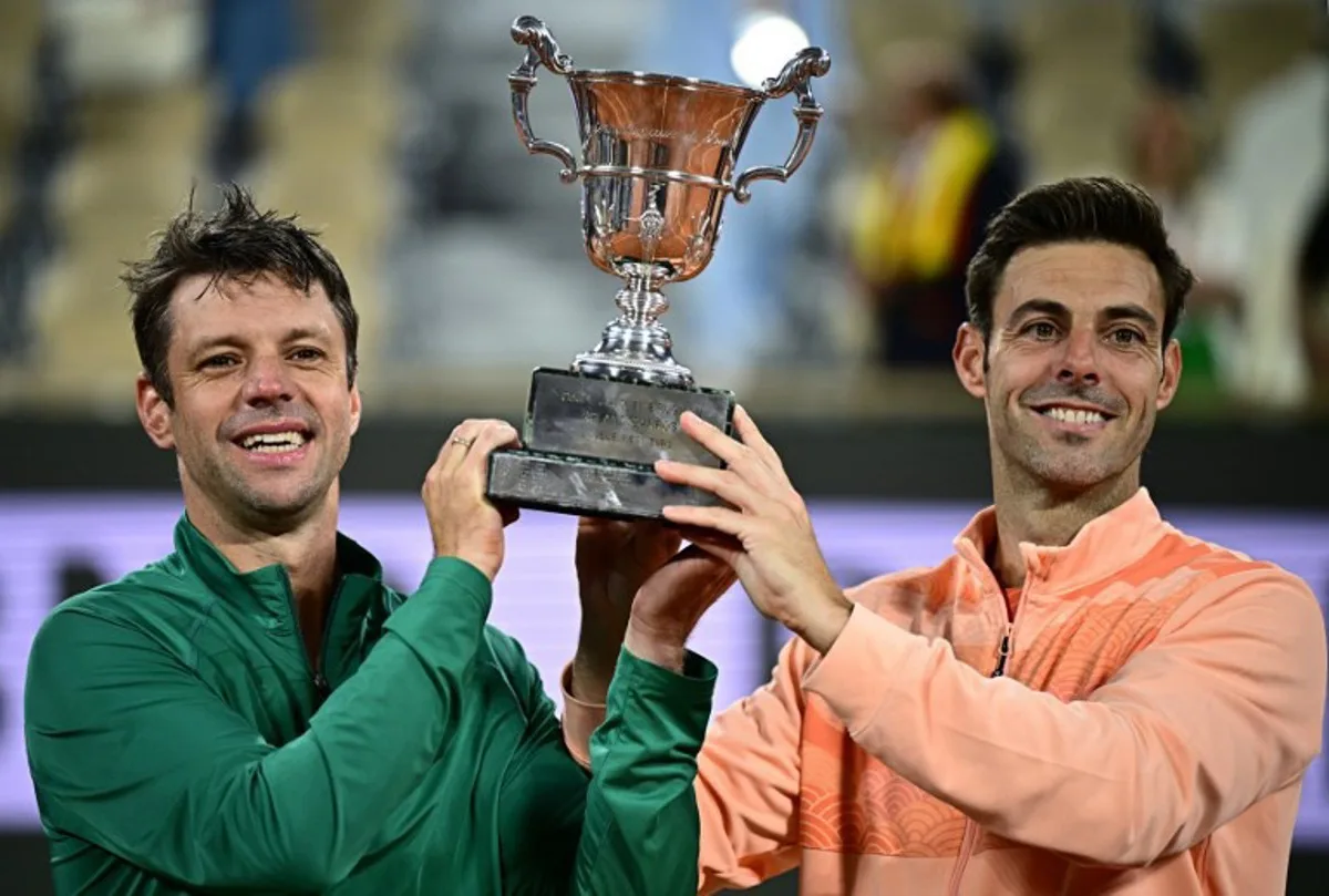 Argentina's Horacio Zeballos (L) and Spain's Marcel Granollers hold their trophy after winning their men's doubles final match against Britain's Joe Salisbury and Britain's Neal Skupski on day 14 of the French Open tennis tournament on Court Philippe-Chatrier at the Roland-Garros Complex in Paris on June 7, 2025. JULIEN DE ROSA / AFP