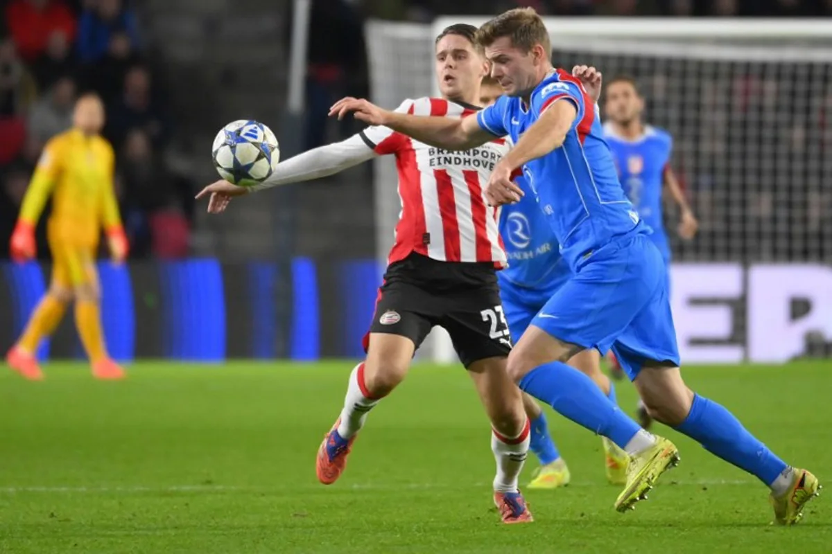 PSV Eindhoven's Dutch midfielder #23 Joey Veerman (L) fights for the ball with Atletico Madrid's Norwegian forward #09 Alexander Sorloth during the UEFA Champions League, league phase day 6, football match between PSV Eindhoven (NED) and Atletico Madrid (ESP), at the Philips Stadion, in Eindhoven, south of The Netherlands, on December 9, 2025.  JOHN THYS / AFP