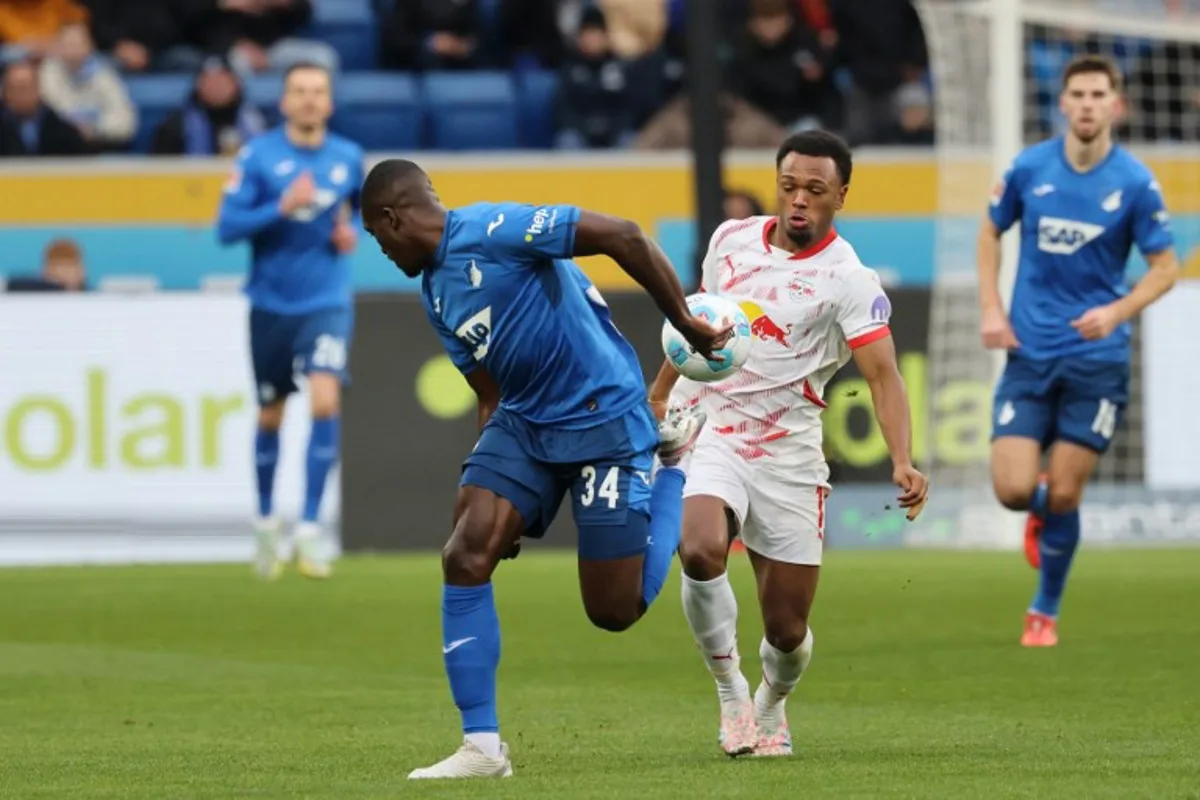 Hoffenheim's French defender #34 Stanley Nsoki (L) and Leipzig's Belgian forward #11 Lois Openda vie for the ball during the German first division Bundesliga football match between TSG 1899 Hoffenheim and RB Leipzig in Sinsheim, southwestern Germany on November 23, 2024.  Daniel ROLAND / AFP