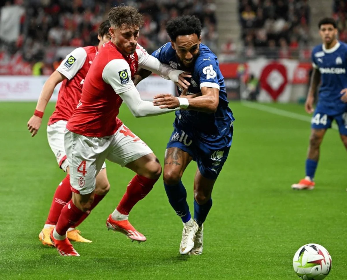 Reims' Belgian defender #04 Maxime Busi (L) fights for the ball with Marseille's French-Gabonese forward #10 Pierre-Emerick Aubameyang during the French L1 football match between Reims And Marseille on May 15, 2024 at Auguste-Delaune stadium in Reims.   FRANCOIS NASCIMBENI / AFP