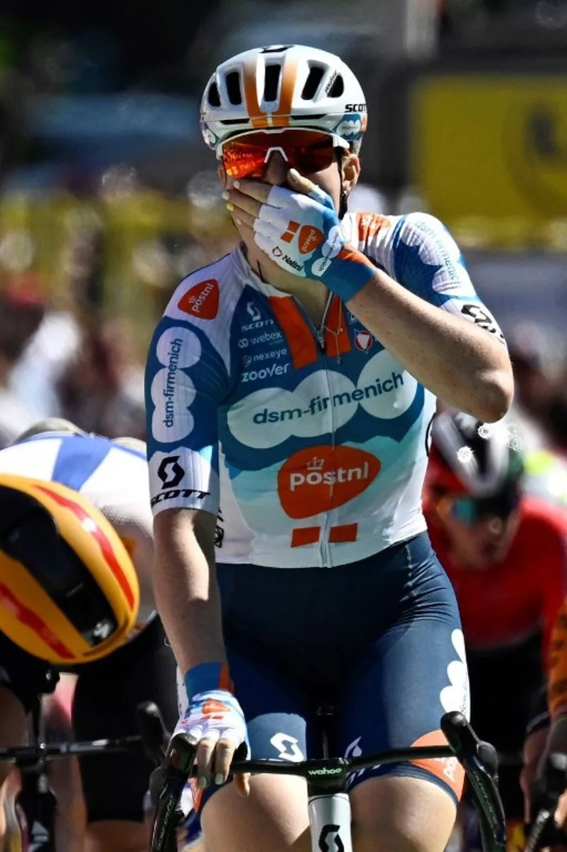 Team DSM-Firmenich PostNL's Dutch rider Charlotte Kool (C) celebrates as she crosses the finish line to win the first stage (out of 8) of the third edition of the Women's Tour de France cycling race, 123 km between Rotterdam and The Hague, on August 12, 2024. JULIEN DE ROSA / AFP