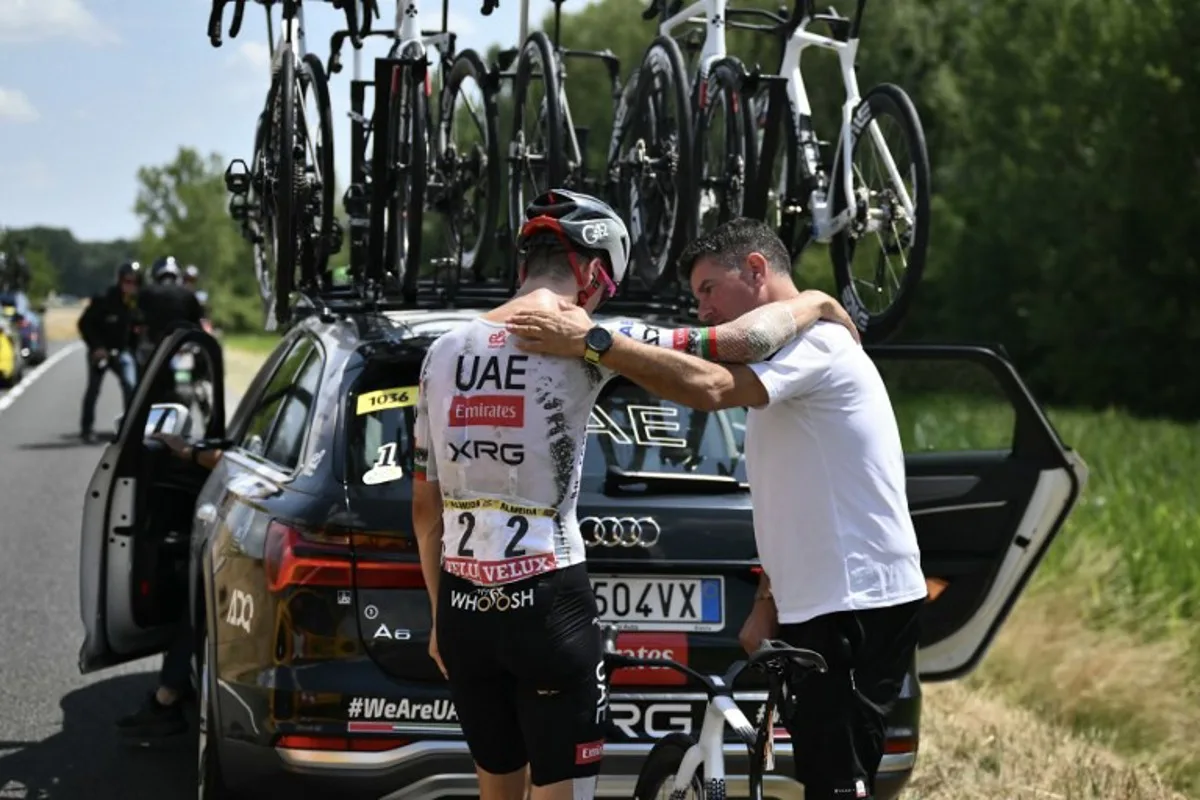 UAE Team Emirates - XRG team's Portuguese rider Joao Almeida is comforted by a team staffed member as he prepared to board his team support vehicle after withdrawing from the race on injury, during the 9th stage of the 112th edition of the Tour de France cycling race, 174.1 km between Chinon and Chateauroux, central France, on July 13, 2025. Marco BERTORELLO / AFP
