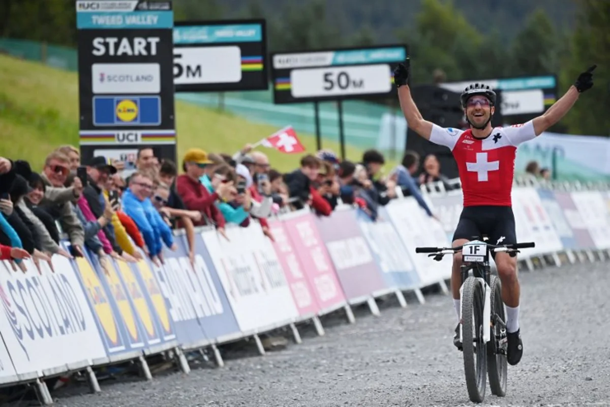 Switzerland's Nino Schurter celebrates winning gold as he crosses the line in the mixed team relay mountain bike cross-country race at the Cycling World Championships in Glentress Forest, Scotland on August 9, 2023. ANDY BUCHANAN / AFP
