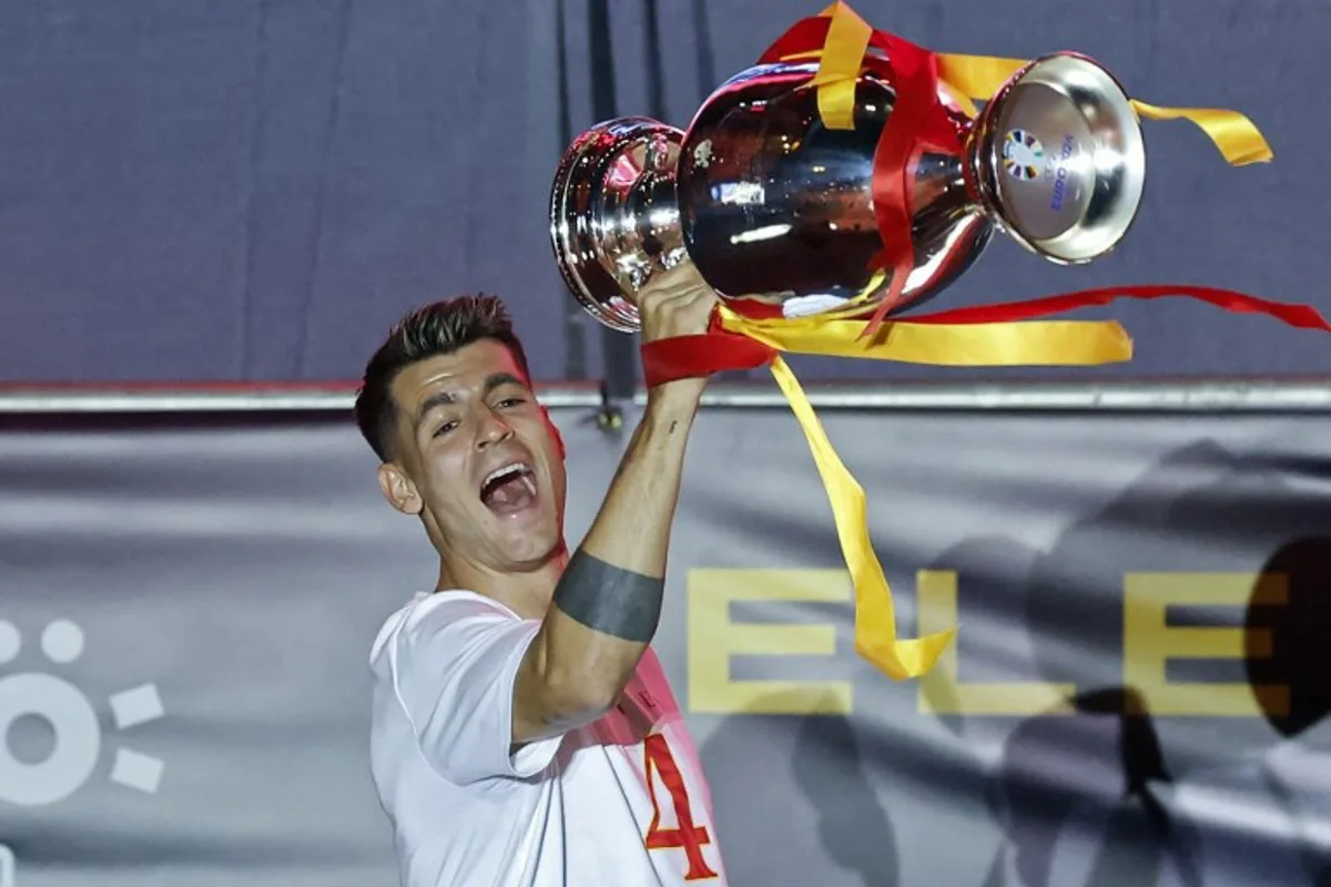 Spain's forward #07 Alvaro Morata celebrates with the trophee as Spanish national football team players celebrate on the stage with fans at Cibeles Square in Madrid on July 15, 2024, after Spain won the UEFA Euro 2024 final football match between Spain and England.   OSCAR DEL POZO / AFP