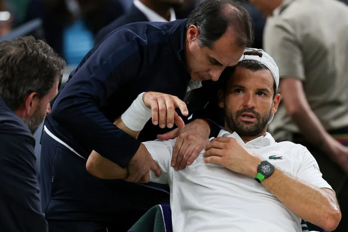 Bulgaria's Grigor Dimitrov reacts as he receives medical treatment after getting injured as he plays against Italy's Jannik Sinner during their men's singles fourth round tennis match on the eighth day of the 2025 Wimbledon Championships at The All England Lawn Tennis and Croquet Club in Wimbledon, southwest London, on July 7, 2025. Adrian Dennis / AFP