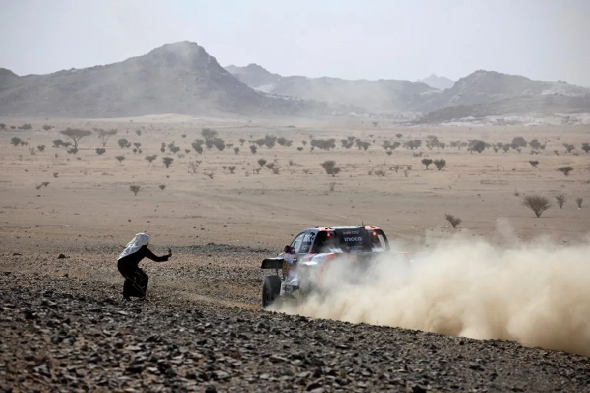 A local resident takes pictures of driver Saood Variawa and co driver Francois Cazalet during the prologue of the 47th Dakar Rally, in Bisha, Saudi Arabia, on January 3, 2025.  Valery HACHE / AFP