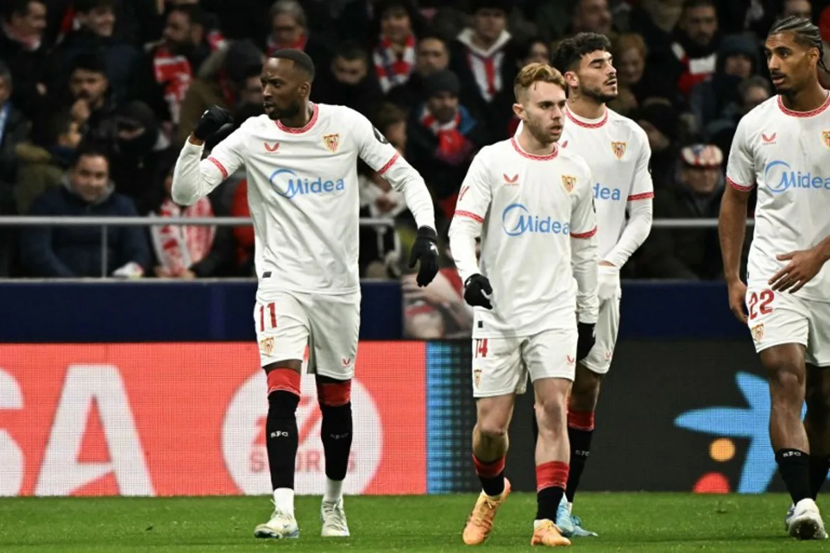 Sevilla's Belgian forward #11 Dodi Lukebakio (L) celebrates after scoring their first goal during the Spanish league football match between Club Atletico de Madrid and Sevilla FC at the Metropolitano stadium in Madrid on December 8, 2024.  JAVIER SORIANO / AFP