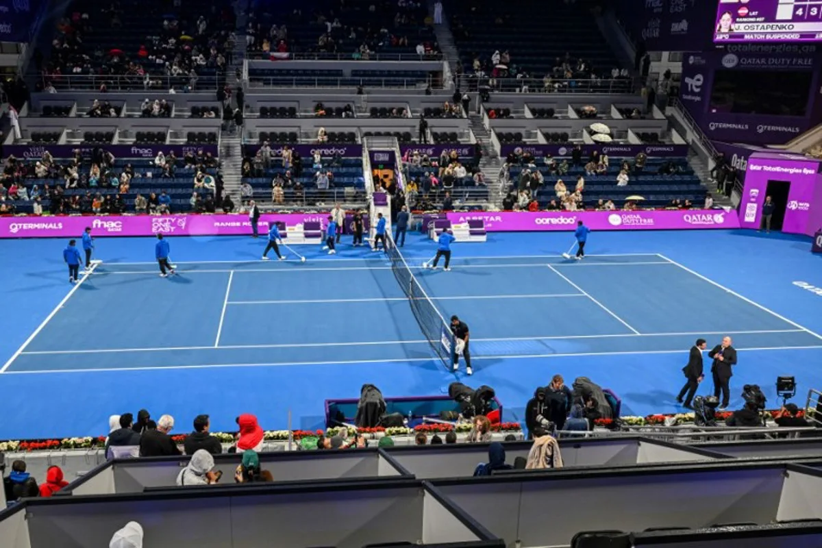 Match officials dry the court as play is suspended due to rain during the 2025 WTA Qatar Open final tennis match bettween Latvia's Jelena Ostapenko and Amanda Anisimova of the US at the Khalifa International Tennis Complex in Doha on February 15, 2025.  Mahmud HAMS / AFP