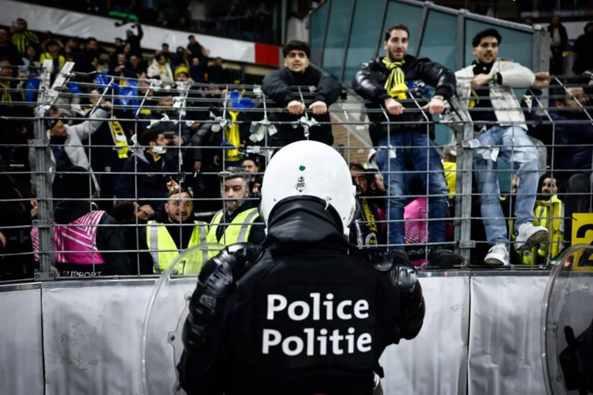 Riot police face Fenerbahce supporters during the UEFA Europa League knockout phase play-off 2nd leg football match between Fenerbahce SK (TUR) and RSC Anderlecht (BEL) at the Lotto Park Stadium in Brussels, on February 20, 2025.  Simon Wohlfahrt / AFP