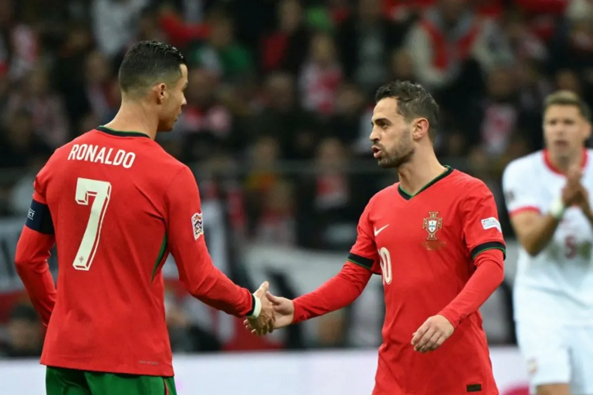 Portugal's midfielder #10 Bernardo Silva (R) celebrates scoring the opening goal with his teammate Portugal's forward #07 Cristiano Ronaldo during the UEFA Nations League, League A Group A1 football match Poland vs Portugal at the National Stadium in Warsaw, Poland on October 12, 2024.  Sergei GAPON / AFP