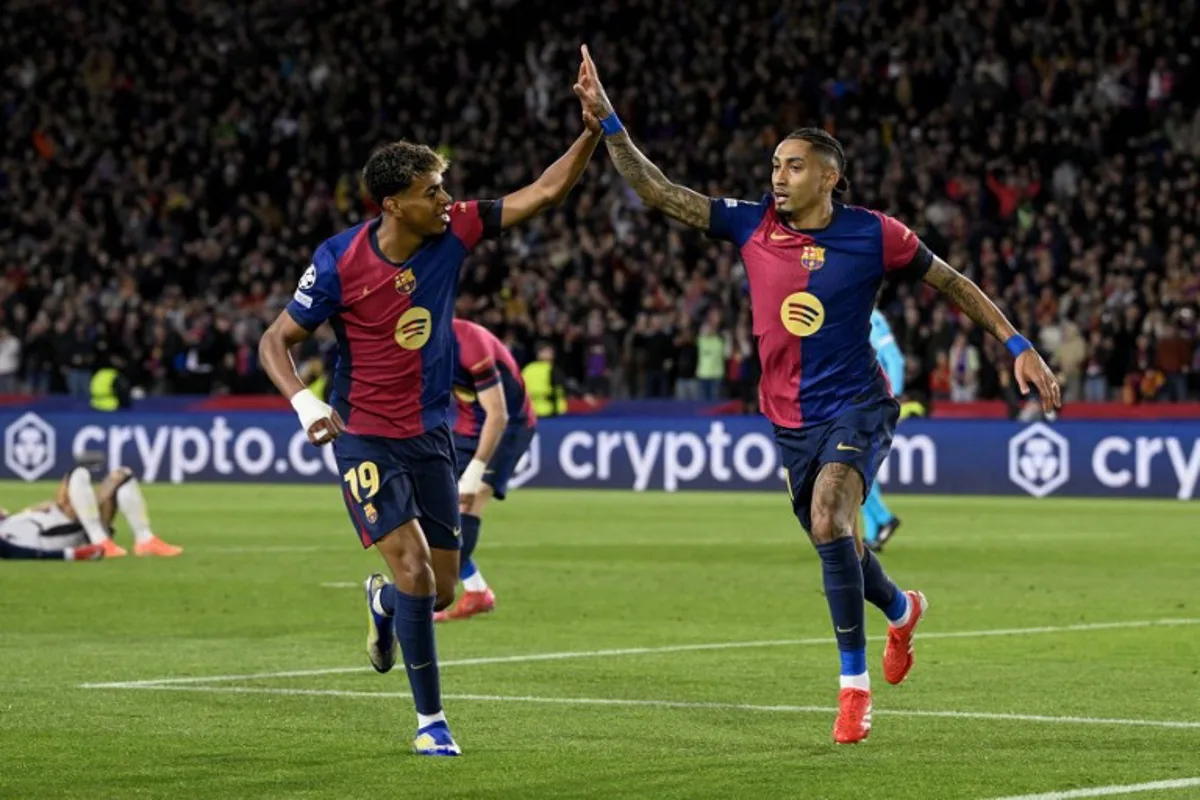 Barcelona's Brazilian forward #11 Raphinha (R) celebrates with Barcelona's Spanish forward #19 Lamine Yamal after scoring his team's third goal during the UEFA Champions League Round of 16 second leg football match between FC Barcelona and SL Benfica at the Estadi Olimpic Lluis Companys in Barcelona on March 11, 2025.   Josep LAGO / AFP