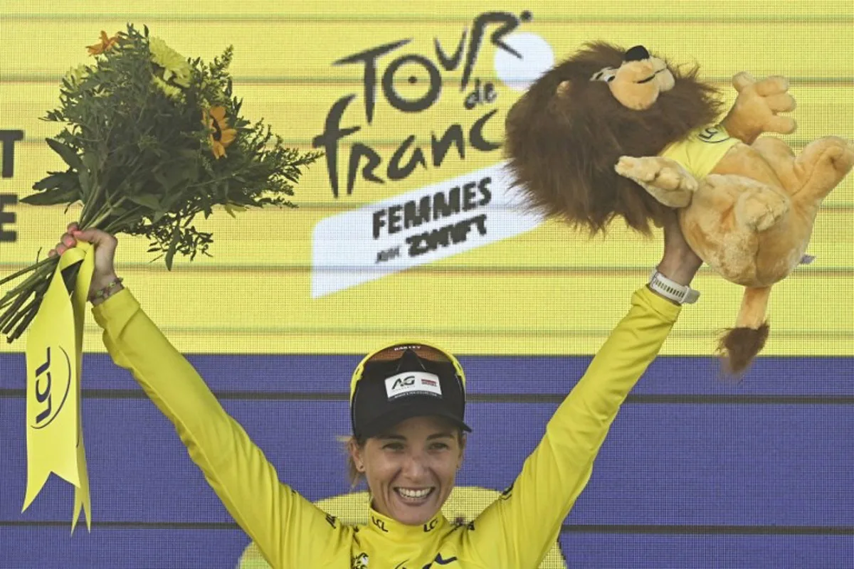 AG Insurance - Soudal Team's Mauritius rider Kimberley Le Court Pienaar celebrates on the podium with the overall leader's yellow jersey after the 5th stage (out of 9) of the fourth edition of the Women's Tour de France cycling race, 165.8 km from Chasseneuil-du-Poitou to Gueret, in Gueret, central France on July 30, 2025. JULIEN DE ROSA / AFP