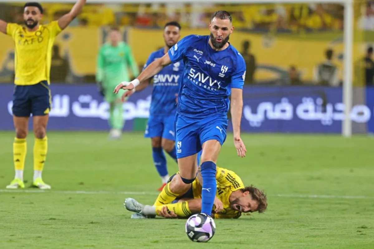 Nassr's Spanish defender #26 Inigo Martinez (down) reacts as Al-Hilal French forward #90 Karim Benzema fights for the ball with during the Saudi Pro League football match between Al-Nassr and Al-Hilal at King Fahd Sports City Stadium in Riyadh on May 12, 2026. Fayez NURELDINE / AFP