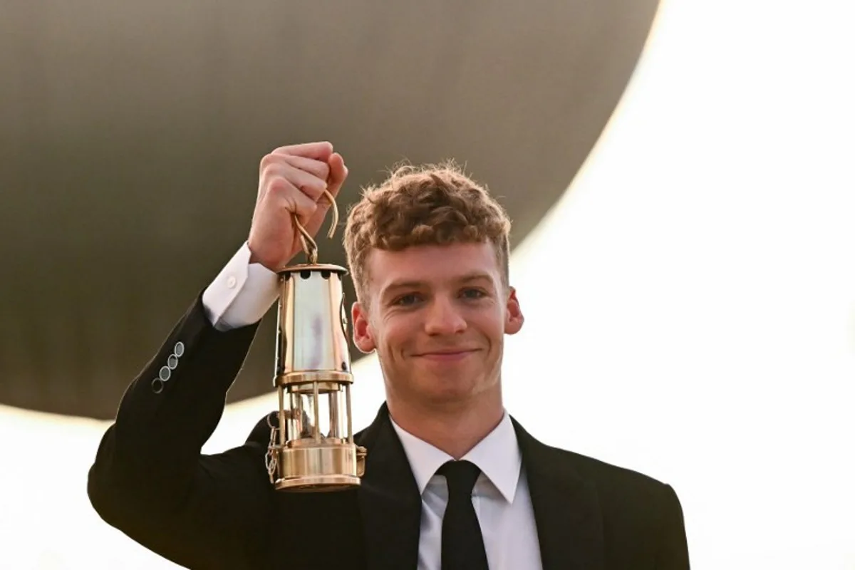 French swimmer Leon Marchand takes the Olympic flame from the cauldron at the Jardin des Tuileries (Tuileries Garden), in Paris, on August 11, 2024, ahead of the closing ceremony of the Paris 2024 Olympic Games.  Loic VENANCE / AFP