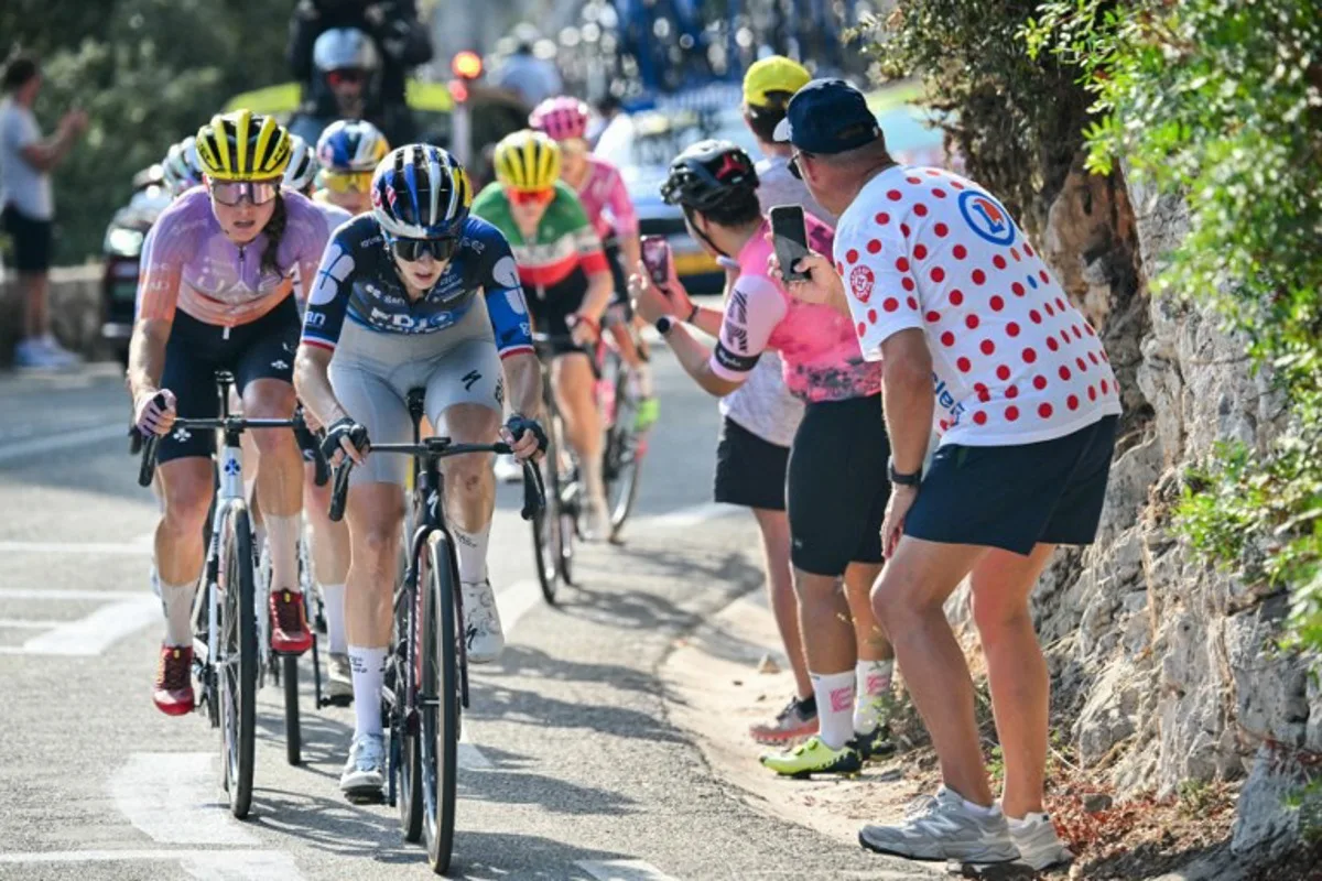 FDJ-SUEZ's French rider Juliette Berthet (C) and UAE Team ADQ's Spanish rider Paula Blasi (L) ride in the peloton in the Col d'Eze during the 9th and final stage of the fifth edition of the Women's Tour de France cycling race, 99.2 km from Nice to Nice, southeastern France on August 9, 2026.  NICOLAS TUCAT / AFP