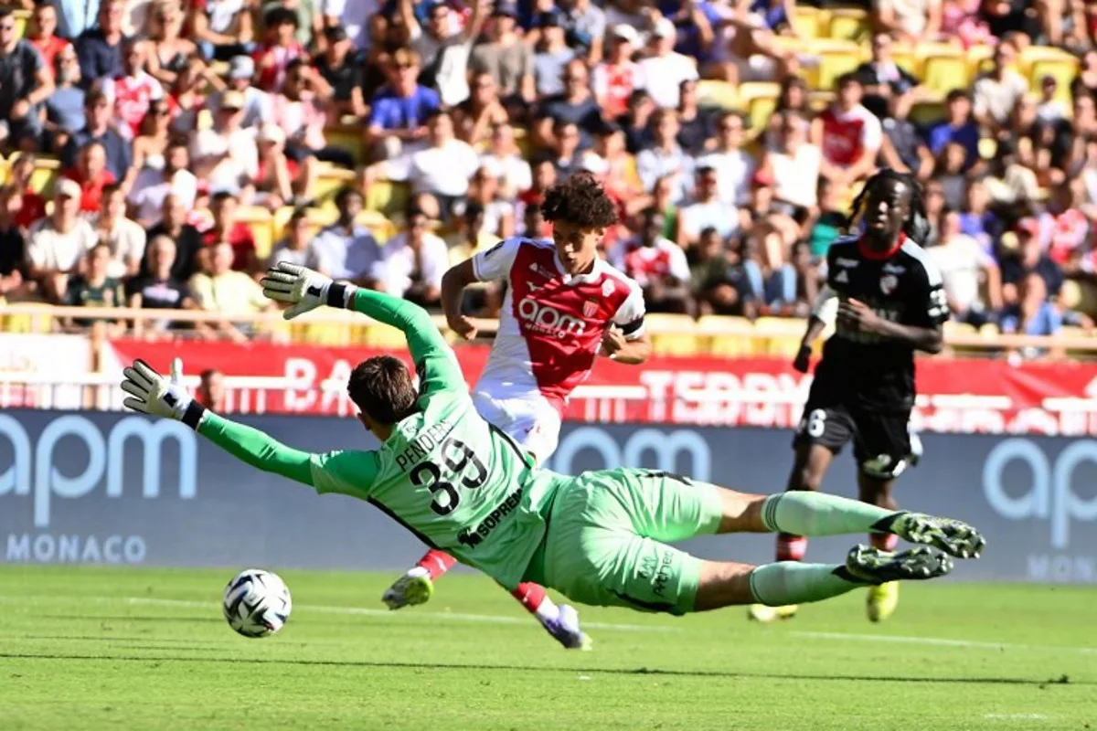 Strasbourg's Belgian goalkeeper #39 Mike Penders (c, down) tries the ball shot by Monaco's French midfielder #11 Maghnes Akliouche (c) during the French L1 football match between AS Monaco and RC Strasbourg Alsace at the Louis II Stadium in the Principality of Monaco on August 31, 2025. FREDERIC DIDES / AFP