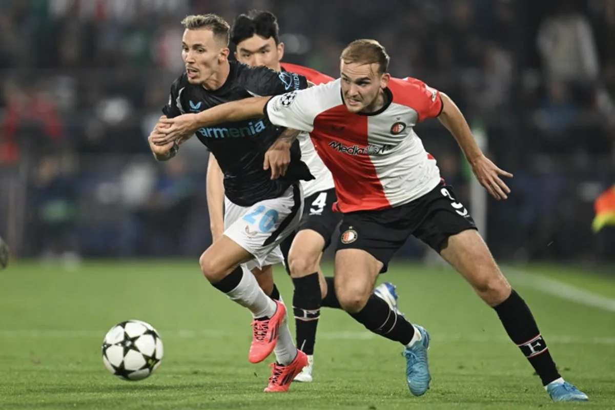 Bayer Leverkusen's Spanish defender #20 Alex Grimaldo (L) fights for the ball with Feyenoord's Dutch defender #03 Thomas Beelen (R) during the UEFA Champions League 1st round day 1 football match between Feyenoord  and Bayer Leverkusen at The De Kuip Stadium, in Rotterdam on September 19, 2024.  JOHN THYS / AFP