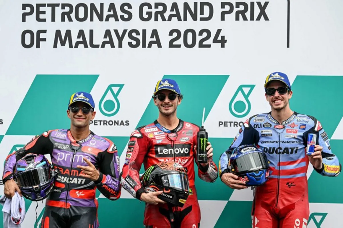 Ducati Lenovo Team's Italian rider Francesco Bagnaia (C) celebrates getting pole position next to second position Prima Pramac Racing's Spanish rider Jorge Martin (L) and third position Gresini Racing MotoGP's Spanish rider Alex Marquez (R) after the qualifying session of the MotoGP Malaysian Grand Prix at the Sepang International Circuit in Sepang on November 2, 2024.  MOHD RASFAN / AFP