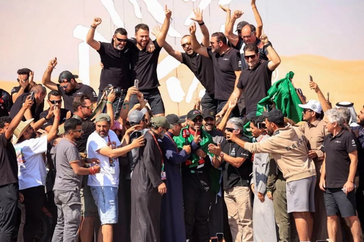 Overdrive Racing's Saudi driver Yazeed Al Rajhi celebrates (Centre-bottom) after winning the Dakar Rally 2025 in the car category at the end of the 12th and last stage in Shubaytah, on January 17, 2025.  Valery HACHE / AFP