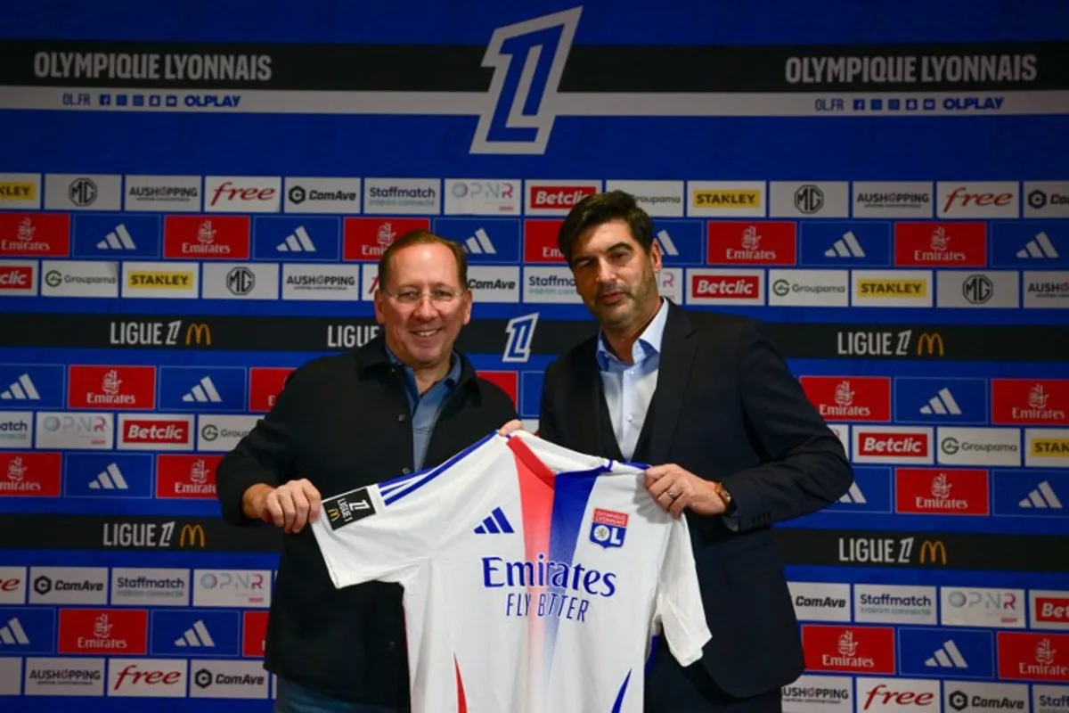 French football club Olympique Lyonnais' (OL) President John Textor (L) and the club's new Portuguese head coach Paulo Fonseca hold a club jersey during a press conference in Decines Charpieu, near Lyon, central-eastern France, on January 31, 2025.  OLIVIER CHASSIGNOLE / AFP