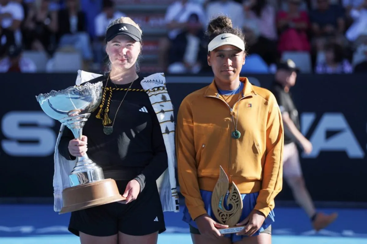 Clara Tauson of Denmark (L) celebrates with the trophy after her win over Naomi Osaka of Japan (R), following Osaka's retirement from their women's singles final match due to an abdominal injury, at the WTA Auckland Classic tennis tournament in Auckland on January 5, 2025.   Michael Bradley / AFP