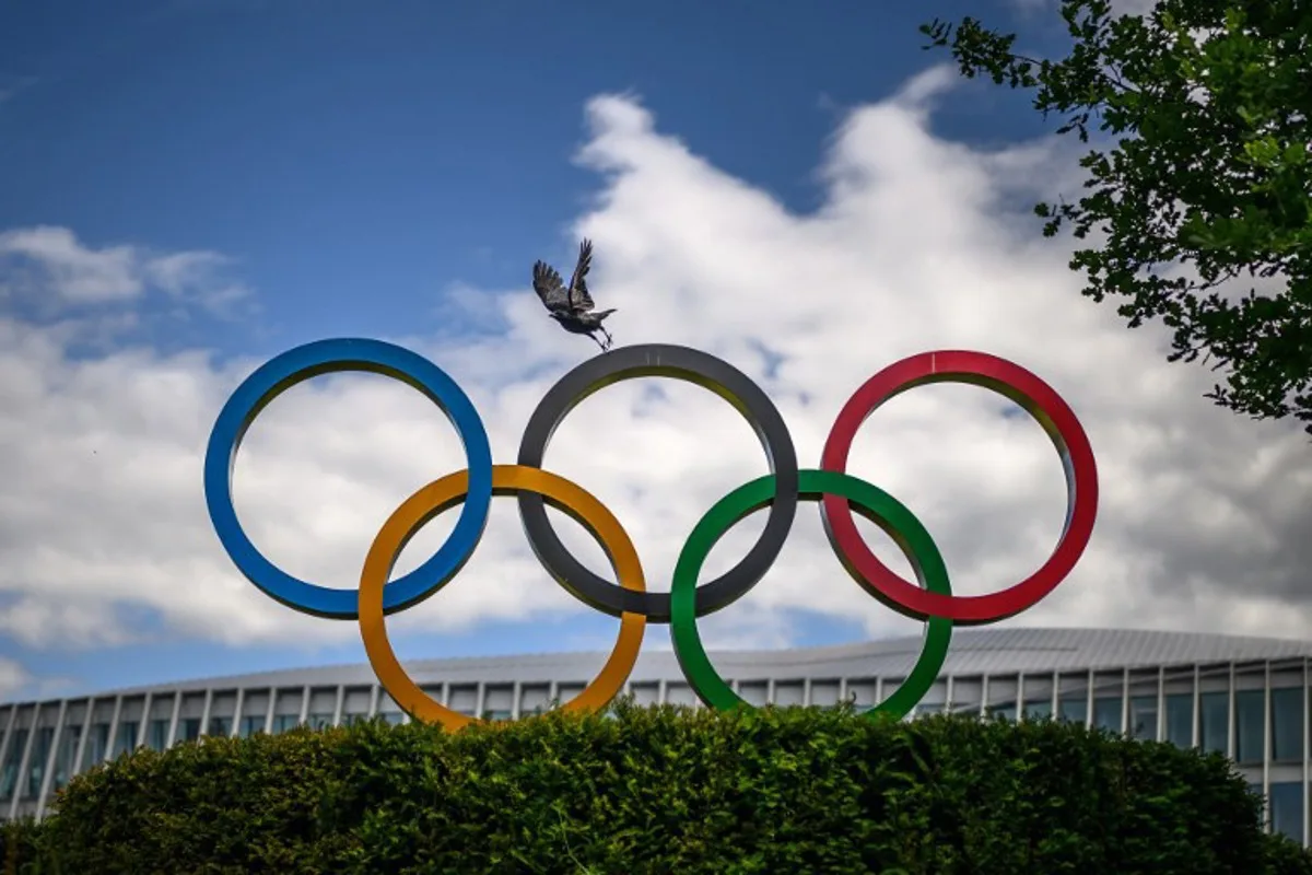 A crow flies above the Olympics Rings displayed at the headquarters of the International Olympic Committee (IOC) in Lausanne on May 13, 2026.  Fabrice COFFRINI / AFP